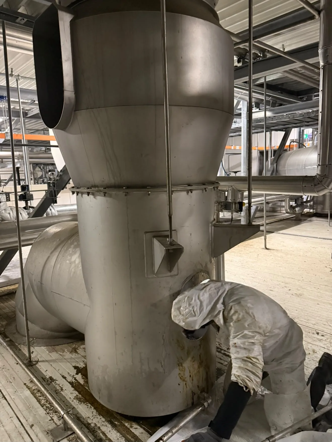 Monteur in beschermpak reinigt een grootkeukeninstallatie