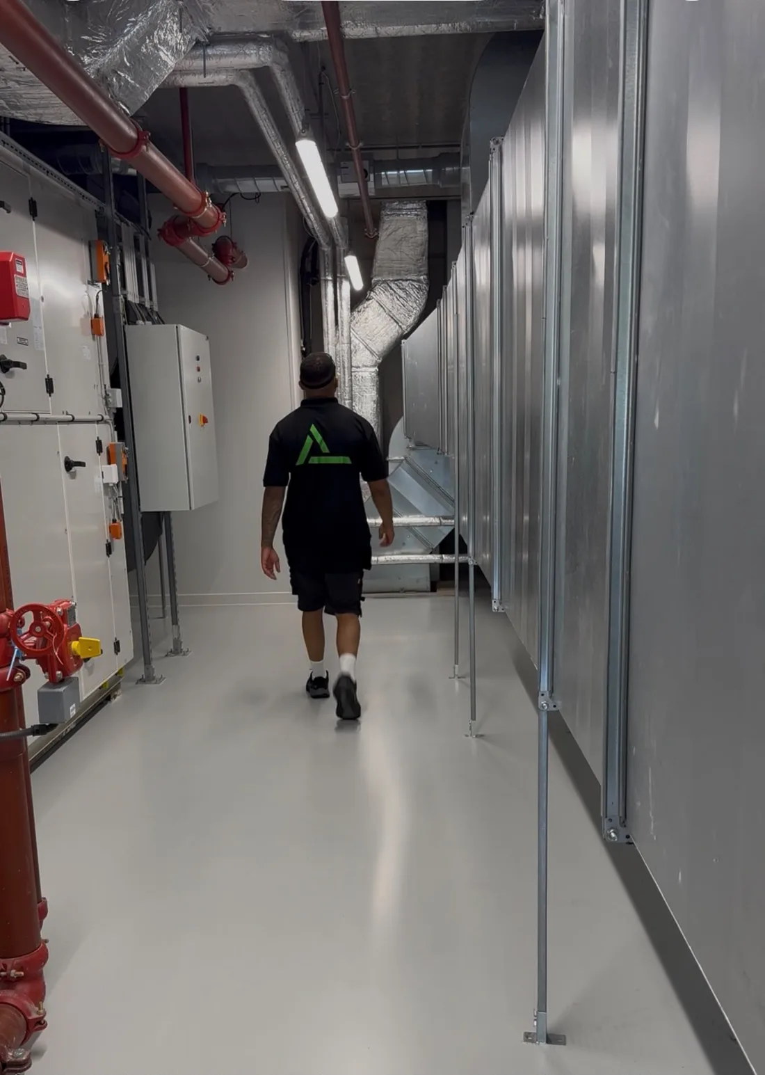 Monteur van All Ventilatie loopt door een technische ruimte met luchtbehandelingskasten
